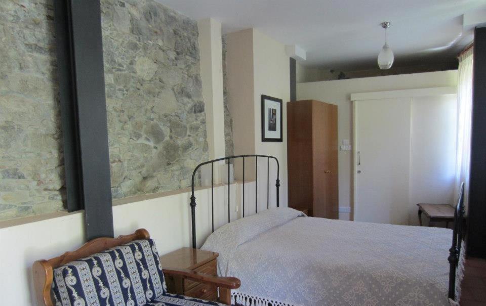 
a bed sitting in a bedroom next to a wall at Ayios Andronikos Agrotourism House in Kalopanayiotis
