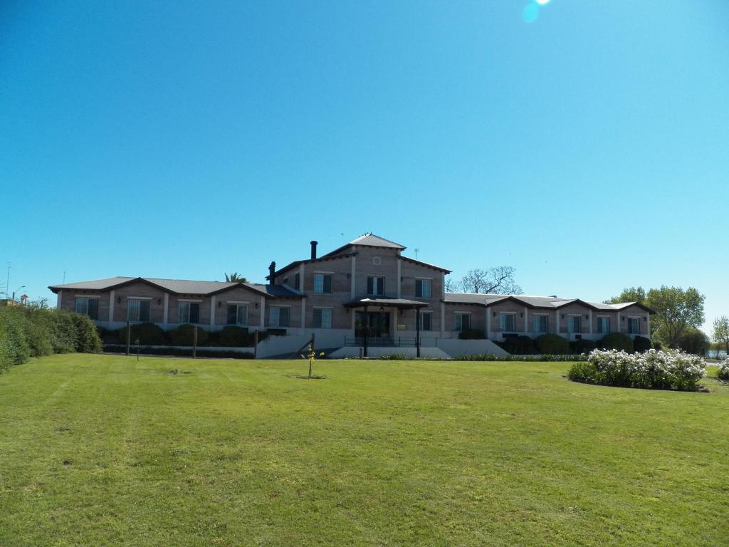 una casa grande con un césped verde delante de ella en Hotel Hostal del Espinillo, en Dolores