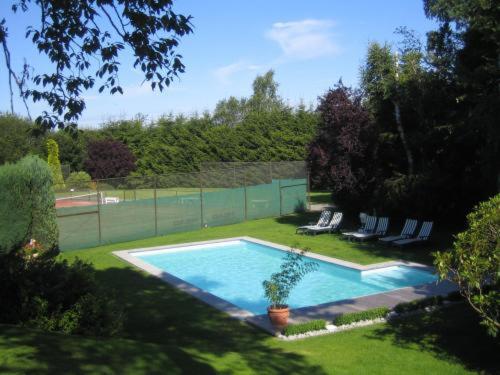 een zwembad in een tuin met stoelen en een hek bij Hotel Hotleu in Waimes