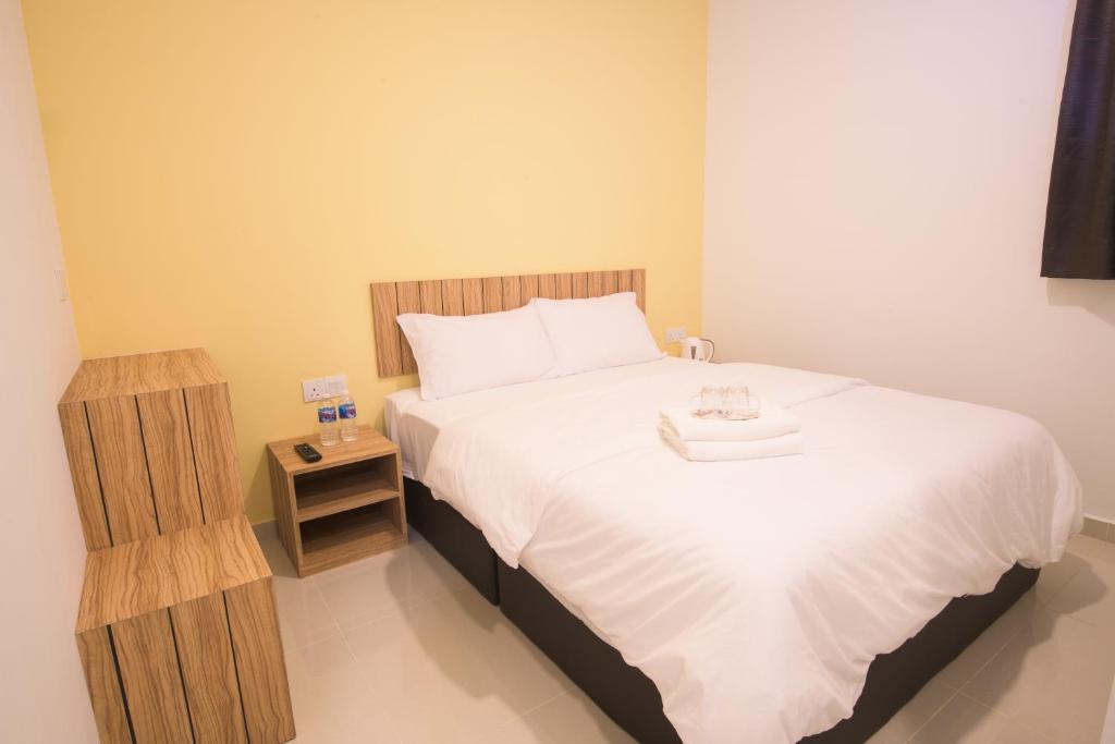 a bedroom with a large bed and a night stand at LTL Guesthouse in Johor Bahru