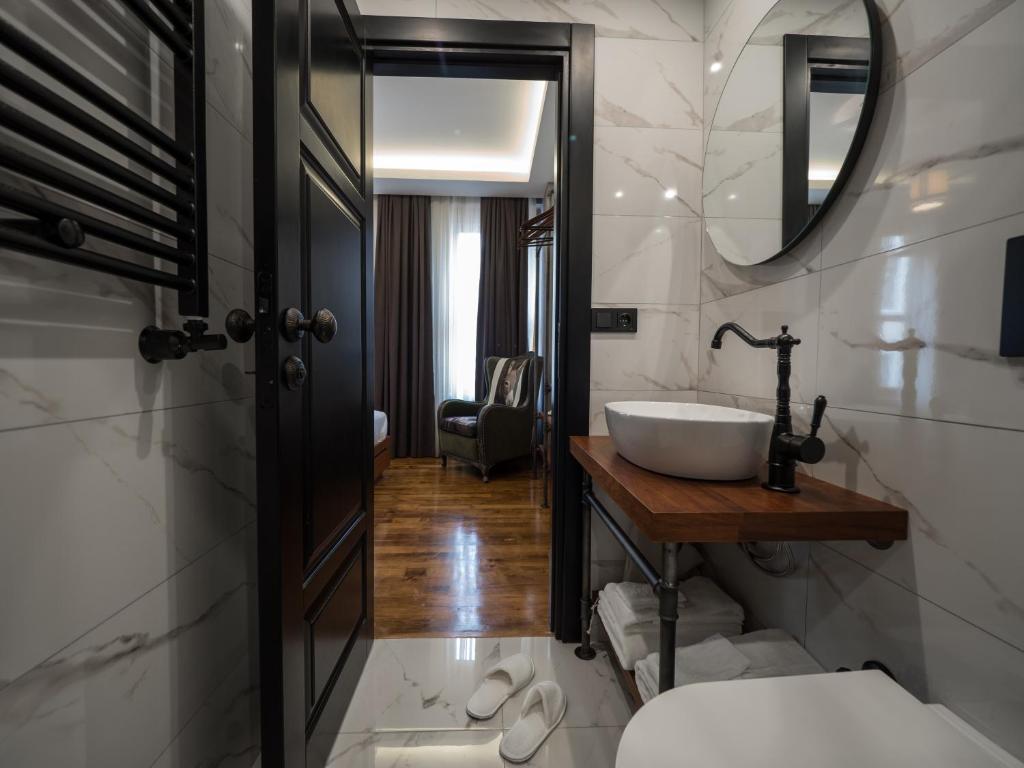 a bathroom with a sink, toilet and mirror at GalataCo Hotel in Istanbul