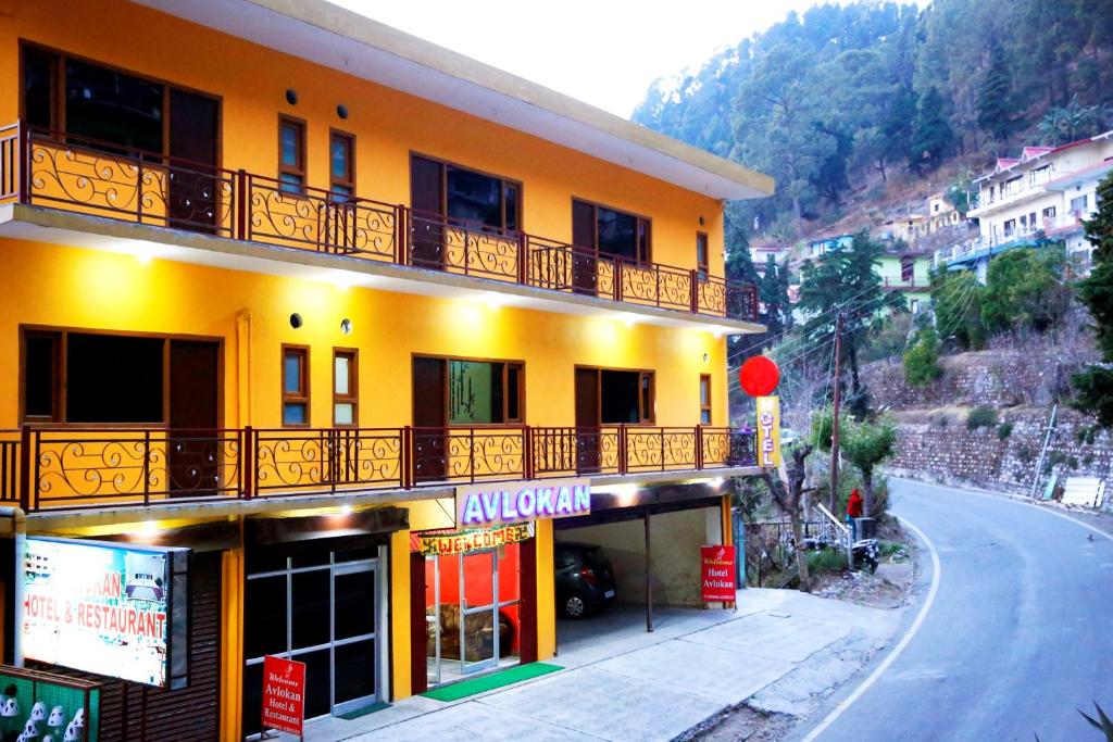 a yellow building with a balcony and a street at Hotel Avlokan - Near Kainchi Dham Mandir in Bhowāli