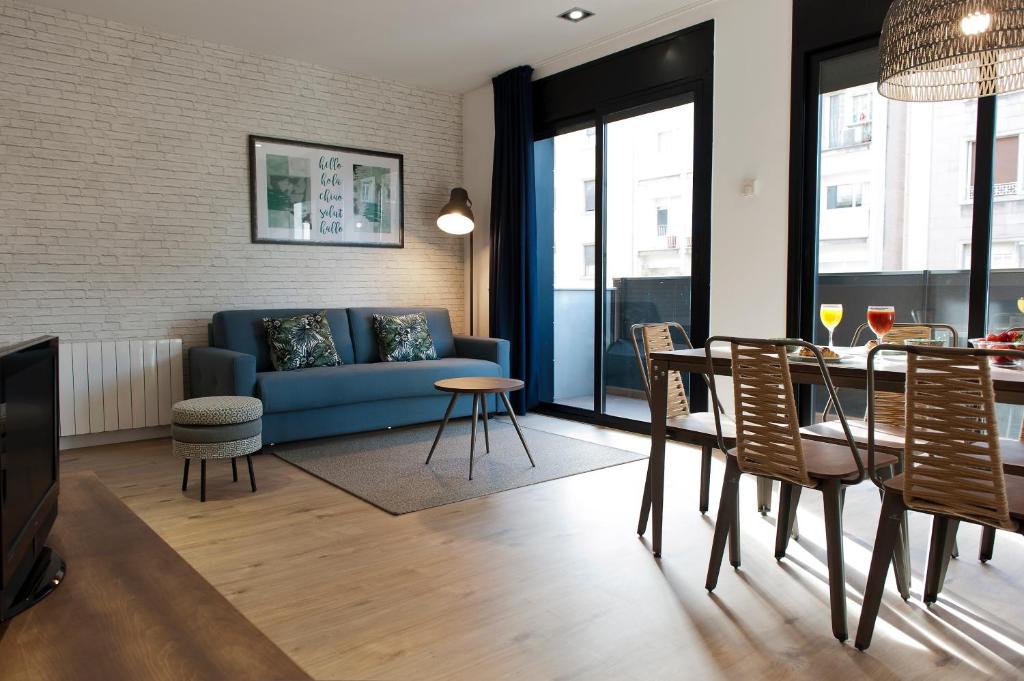 MH Apartments Sant Pau في برشلونة: غرفة معيشة مع أريكة زرقاء وطاولة