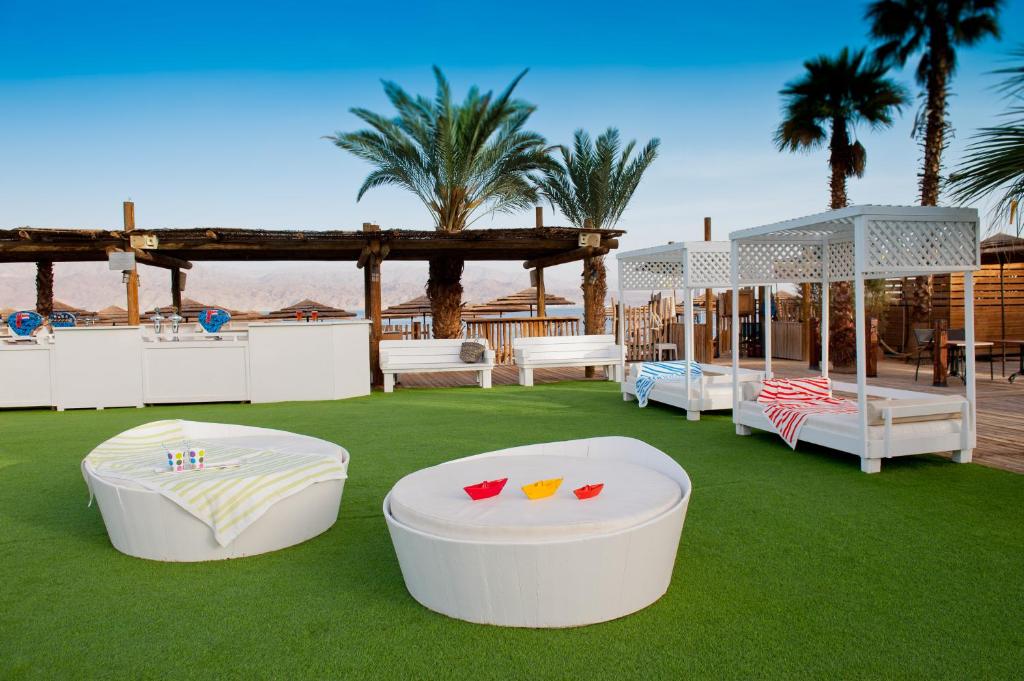 2 weiße Betten auf einem Rasen mit Palmen in der Unterkunft U Coral Beach Club Eilat – Ultra All inclusive in Eilat