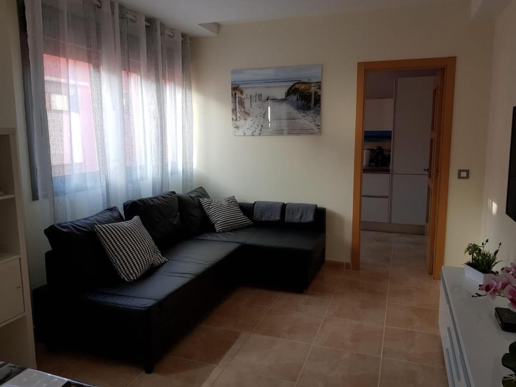 a living room with a black couch in a room at Alojamiento Ramon Cortez in Puerto del Rosario