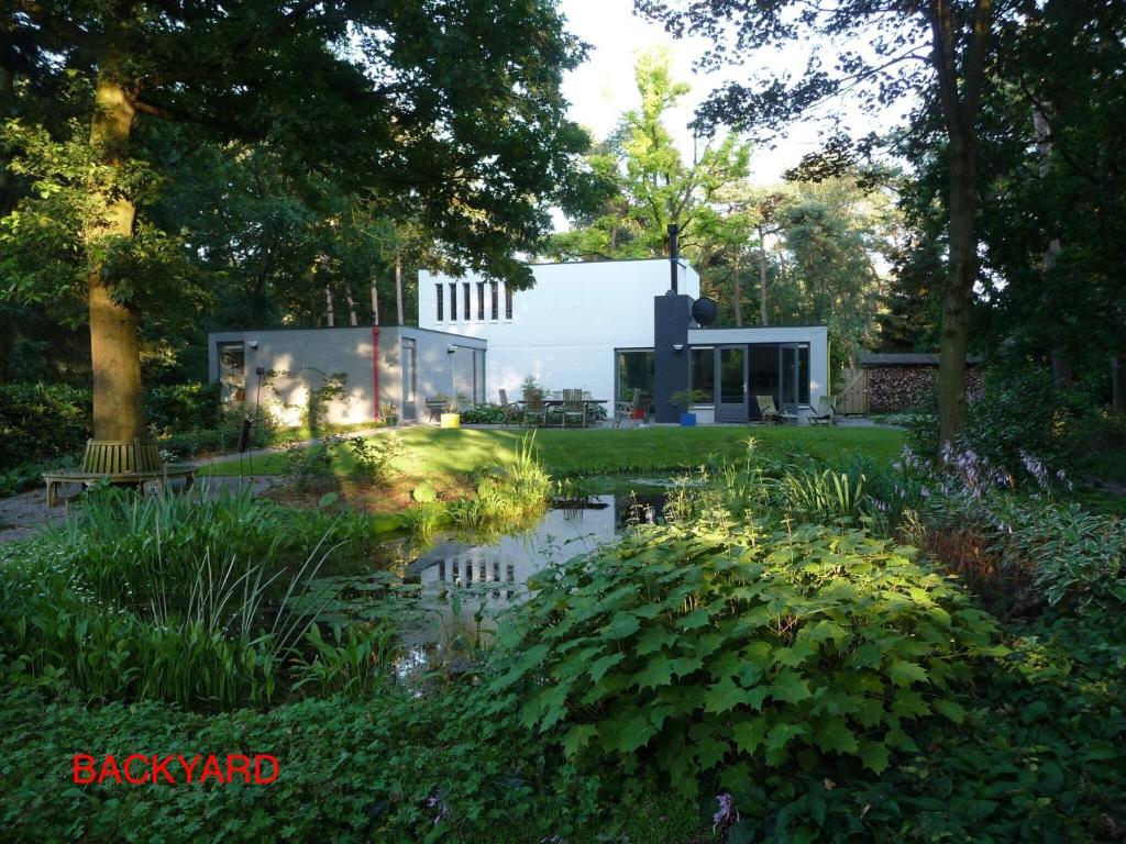 a glass house in a garden with a pond at B & B De Stijl in Vessem