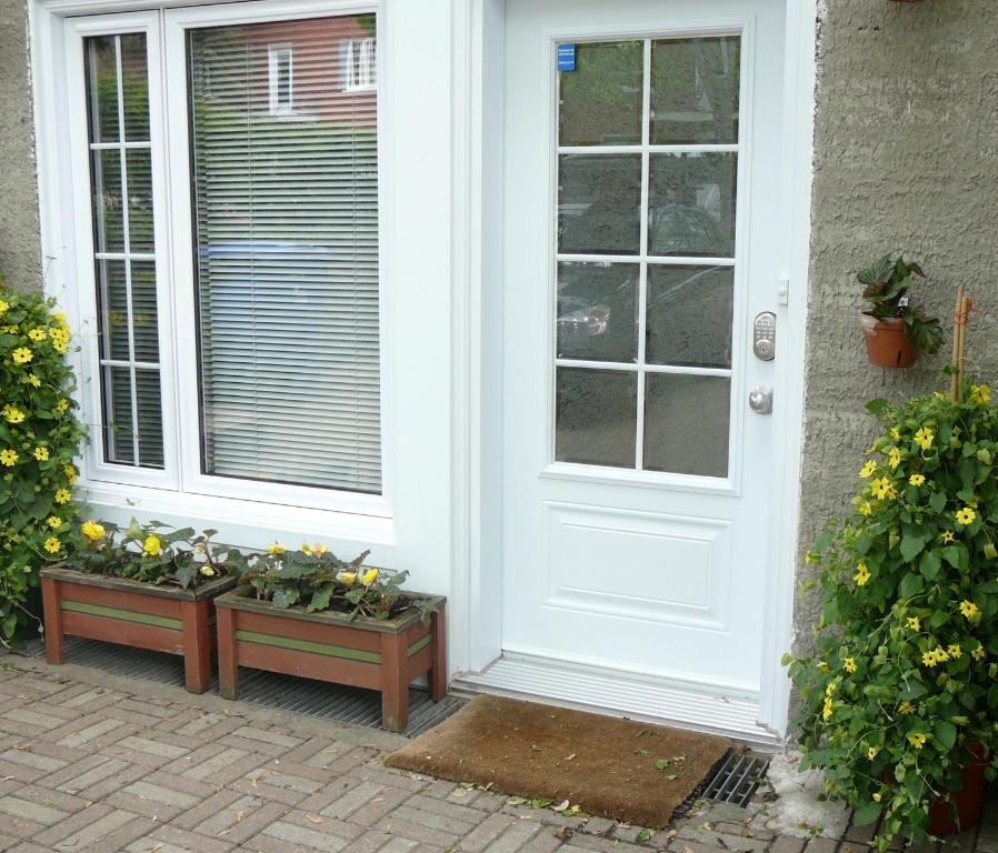 una puerta blanca con un montón de plantas sentadas afuera en B&B La Bedondaine, en Quebec