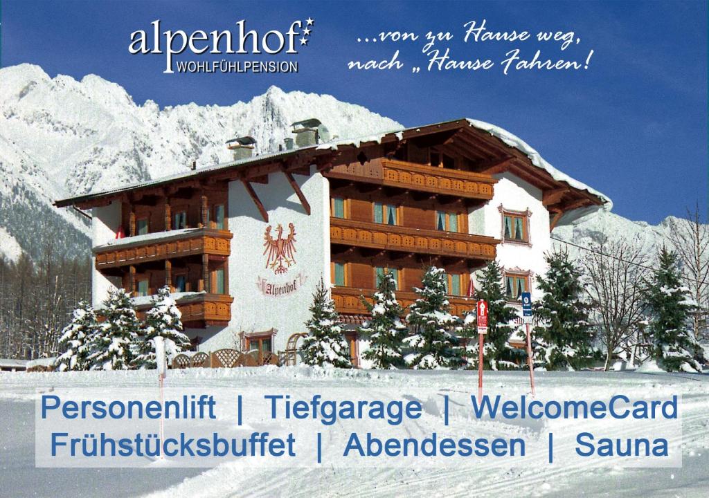a building in the snow in front of a mountain at Alpenhof Wohlfühlpension in Obsteig