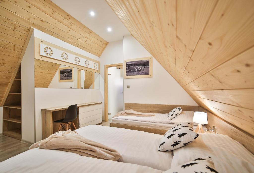 two beds in a room with wooden walls at Apartamenty Kościelisko in Kościelisko