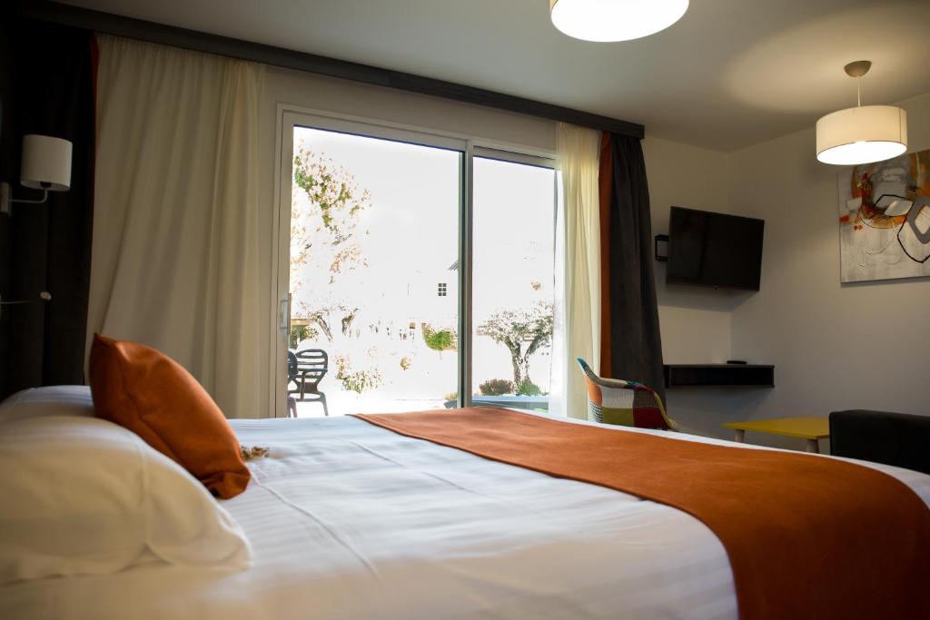 a hotel room with a bed with a large window at Le Domaine des Oliviers in Pierrelatte