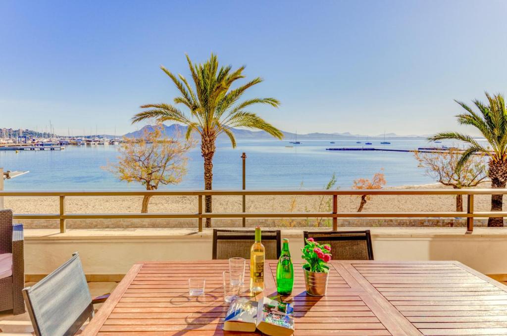a table with wine bottles and flowers on a beach at Emma Beachfront Apartment by Sealand Villas in Port de Pollensa
