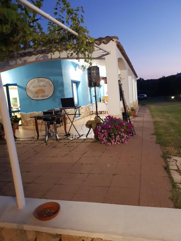 a building with a patio with a table and flowers at Hotel Baia Cea in Bari Sardo