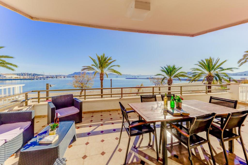 a balcony with tables and chairs and a view of the water at Emma Beachfront Apartment in Port de Pollensa