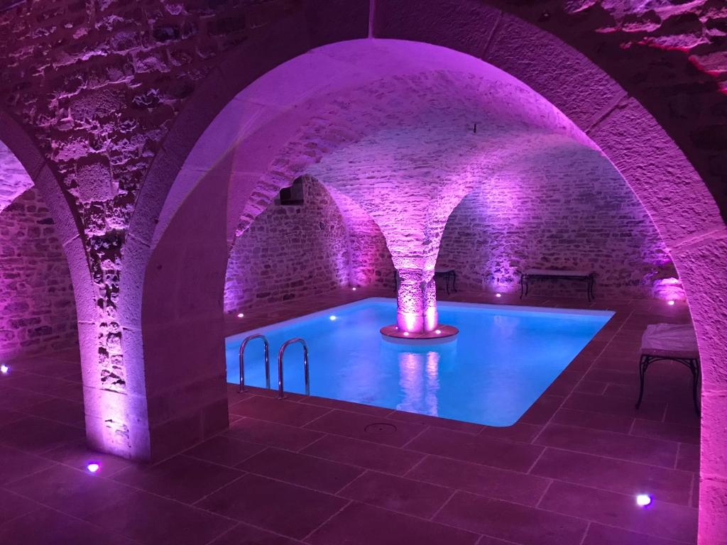uma piscina num quarto de tijolos com iluminação roxa em Domaine de la Corgette em Saint-Romain