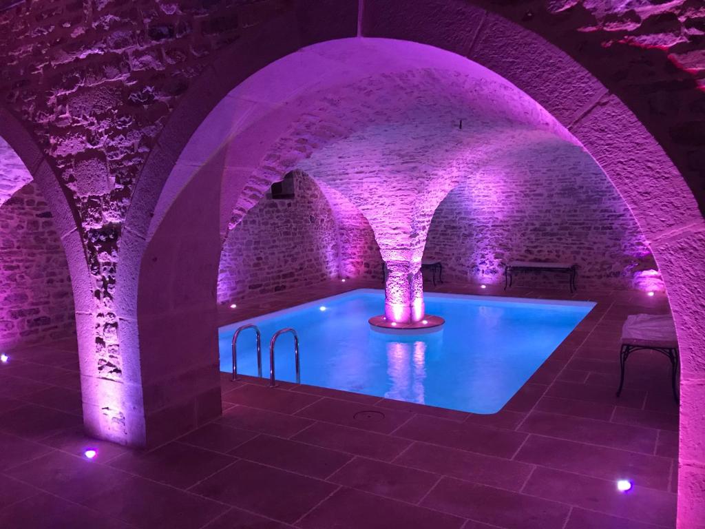 una piscina in una camera in mattoni con illuminazione viola di Domaine de la Corgette a Saint-Romain