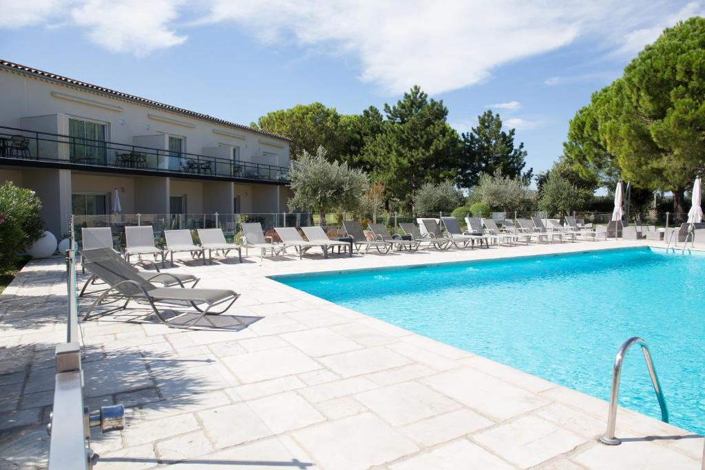 a swimming pool with lounge chairs and a resort at Le Domaine des Oliviers in Pierrelatte