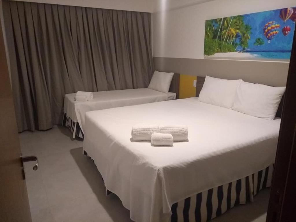 Apto Resort Olimpia في أوليمبيا: سريرين في غرفة فندق مع مناشف عليهما