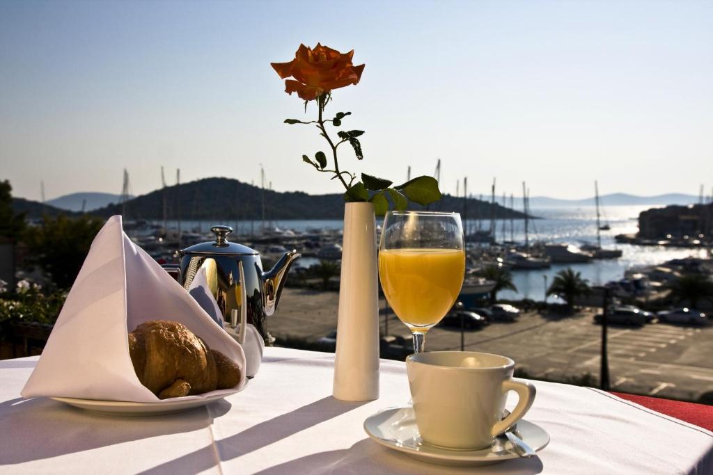 uma mesa com um copo de vinho e um vaso com uma flor em Villa Diana em Tribunj