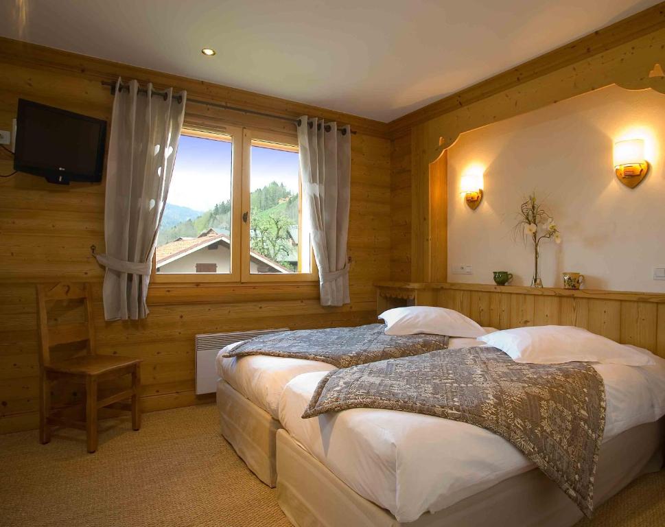 a bedroom with two beds and a large window at La ferme de sixt chambre proche La Clusaz et Grand Bornand in Saint-Jean-de-Sixt