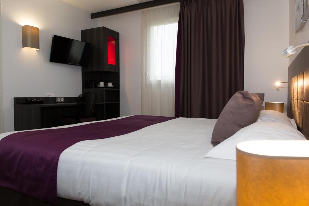 a hotel room with a bed and a television at Le Domaine des Oliviers in Pierrelatte