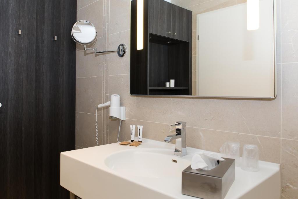a bathroom with a white sink and a mirror at Le Domaine des Oliviers in Pierrelatte