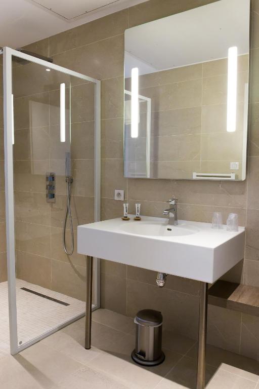 a bathroom with a white sink and a shower at Le Domaine des Oliviers in Pierrelatte