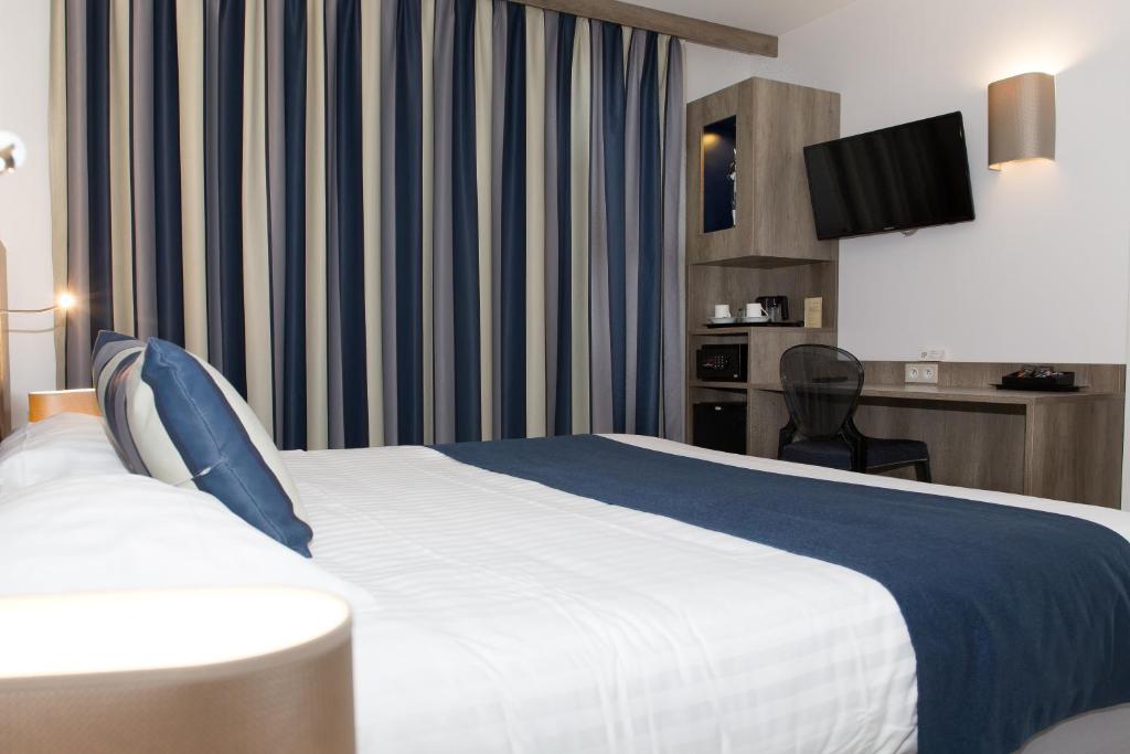 a hotel room with a bed and a tv at Le Domaine des Oliviers in Pierrelatte