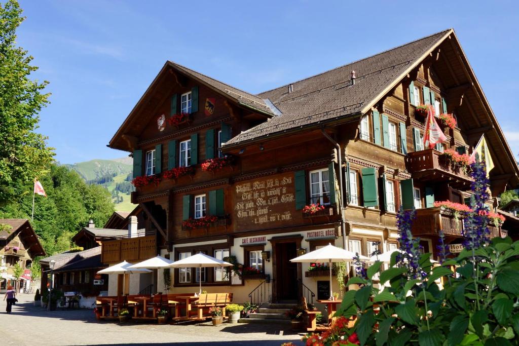 un bâtiment avec des tables et des parasols devant lui dans l'établissement Posthotel Rössli, à Gstaad