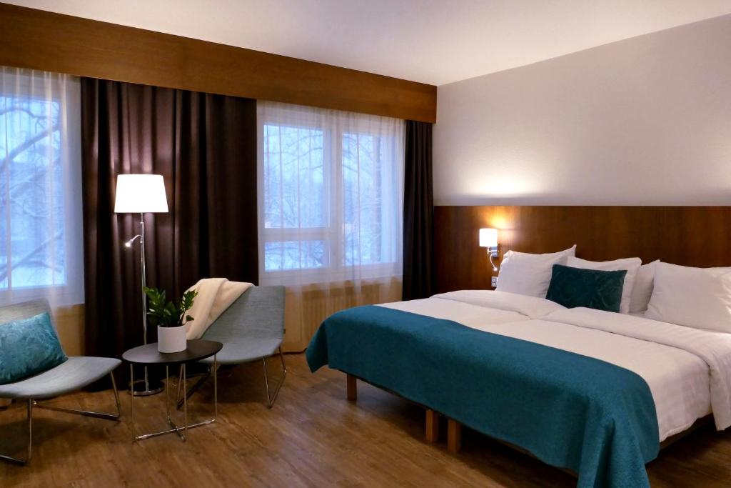 ラウマにあるHotel Raumanlinnaの大きなベッド、テーブル、椅子が備わるホテルルームです。