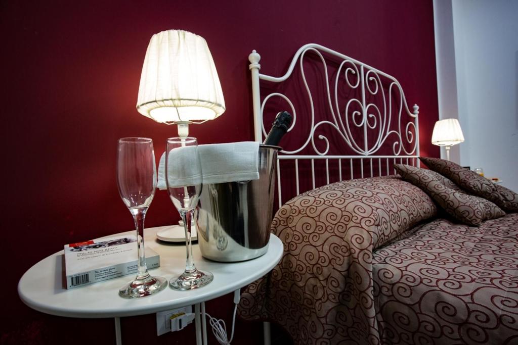een slaapkamer met een bed en een tafel met wijnglazen bij Casa Florio Appartamenti in Palermo