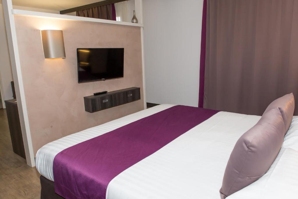 a bedroom with a bed and a tv on a wall at Le Domaine des Oliviers in Pierrelatte