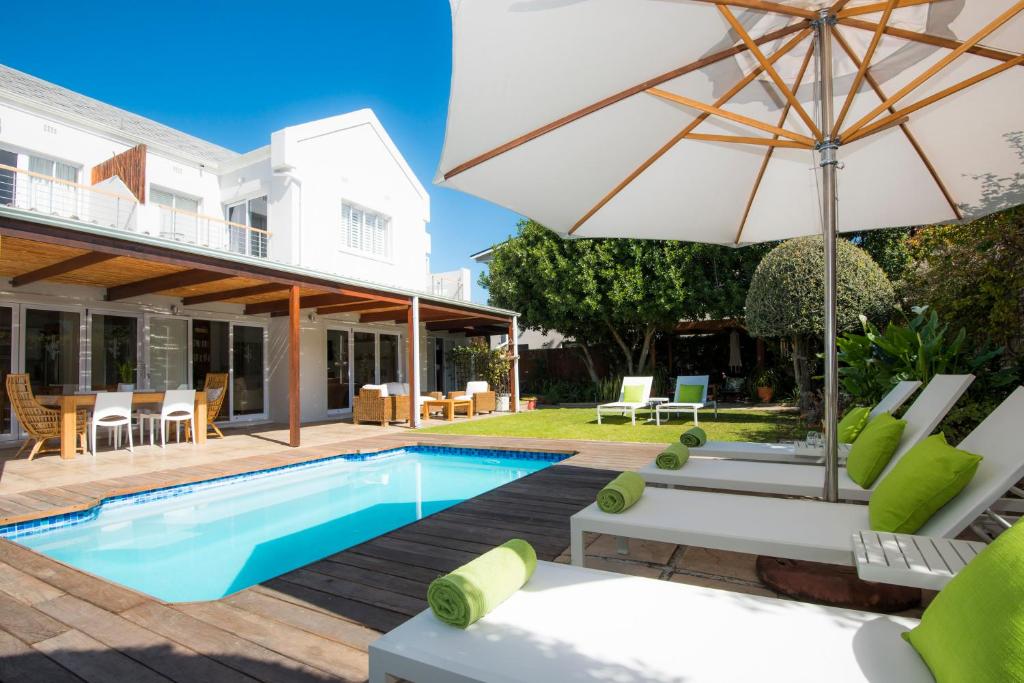 a patio with a pool and an umbrella at Bamboo Guest House in Hermanus