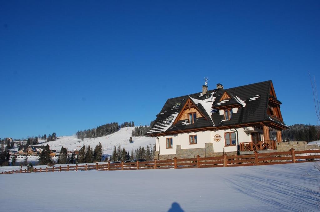 a house with a snow covered roof on top of a field at Willa Misiowa Chata in Czarna Góra