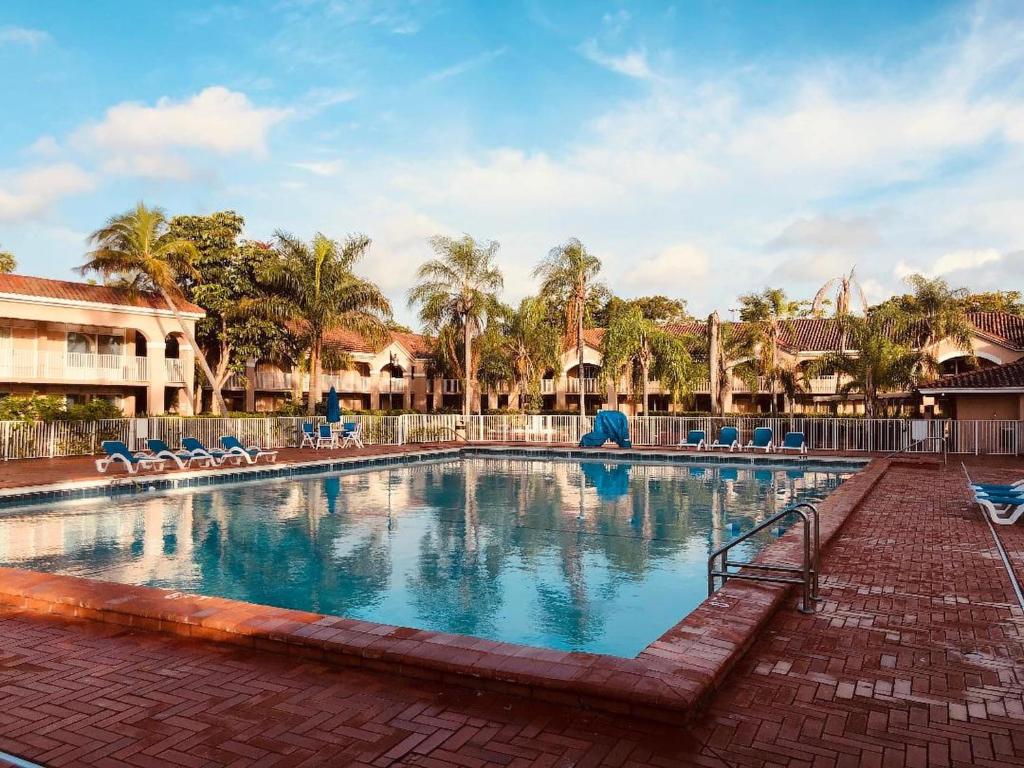 une piscine dans un complexe hôtelier avec des chaises et des palmiers dans l'établissement Grand Palms Spa & Golf Resort, à Pembroke Pines