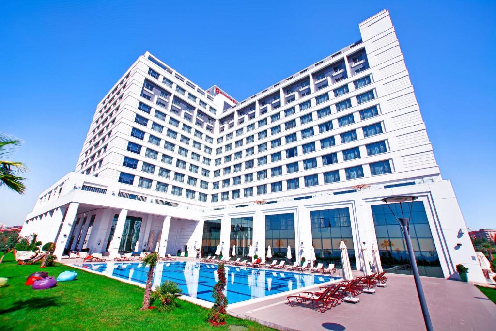 un gran edificio con una piscina frente a él en The Green Park Pendik, en Estambul