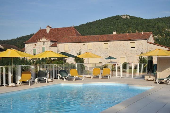 a swimming pool with chairs and umbrellas next to a building at Le Mas de La Pommeraie in Saint-Géry