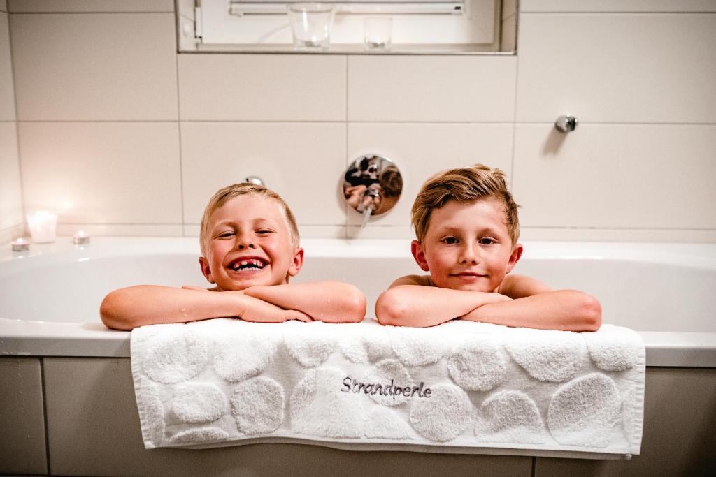 zwei Kinder liegen in einer Badewanne in der Unterkunft Ferienhaus Nordbrise in Dranske