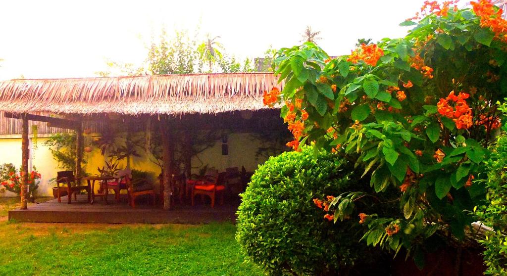 a house with a thatch roof and a yard with flowers at The Garden in Thong Sala