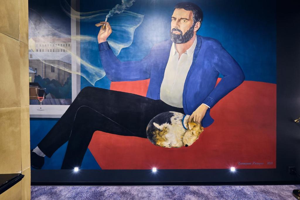 um cartaz de um homem sentado numa cadeira com um cão em Underwood Art Room em São Petersburgo