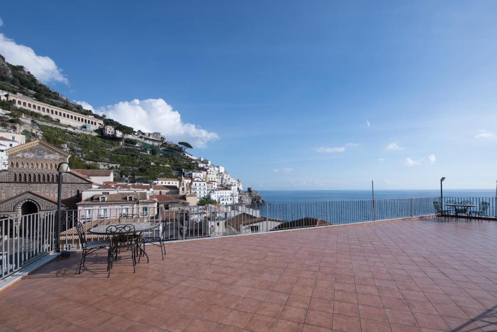 une terrasse avec une table et des chaises et l'océan dans l'établissement Amalfitano Apartments, à Amalfi