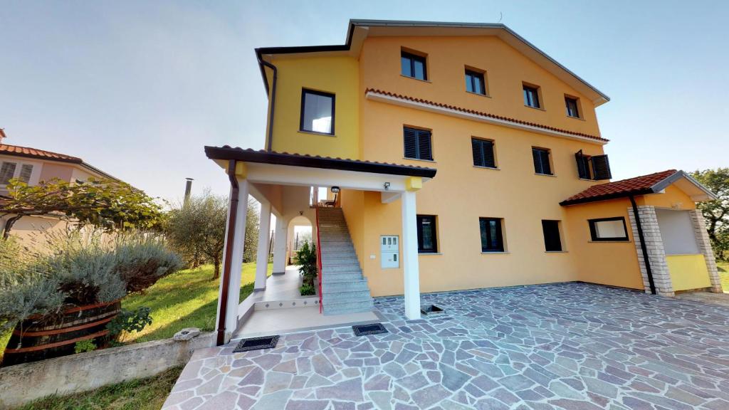 a large yellow house with a driveway at Apartments Goga in Umag