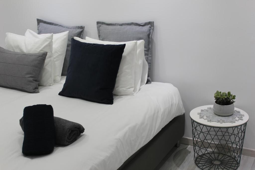 a bed with black and white pillows and a side table at Olosuites in Limassol