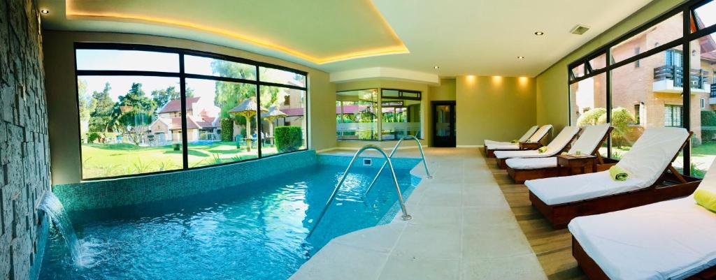a swimming pool in a hotel with several beds and windows at Paradiso Hotel in Merlo