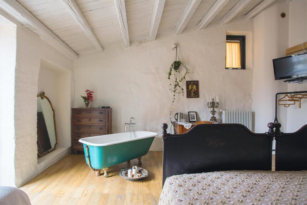 a bedroom with a tub and a bed and a television at WUNDERGARTEN Dimora dei Frati in Gratteri