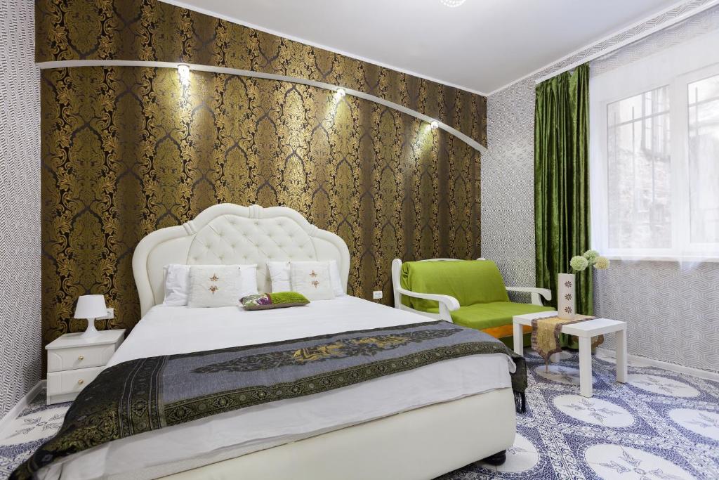 1 dormitorio con 1 cama blanca y 1 silla verde en Apartments near Opera House, en Leópolis