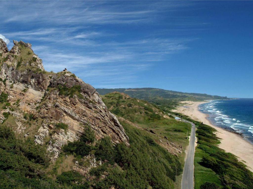 a road on the side of a mountain next to the ocean at Santosha Barbados in Saint Andrew