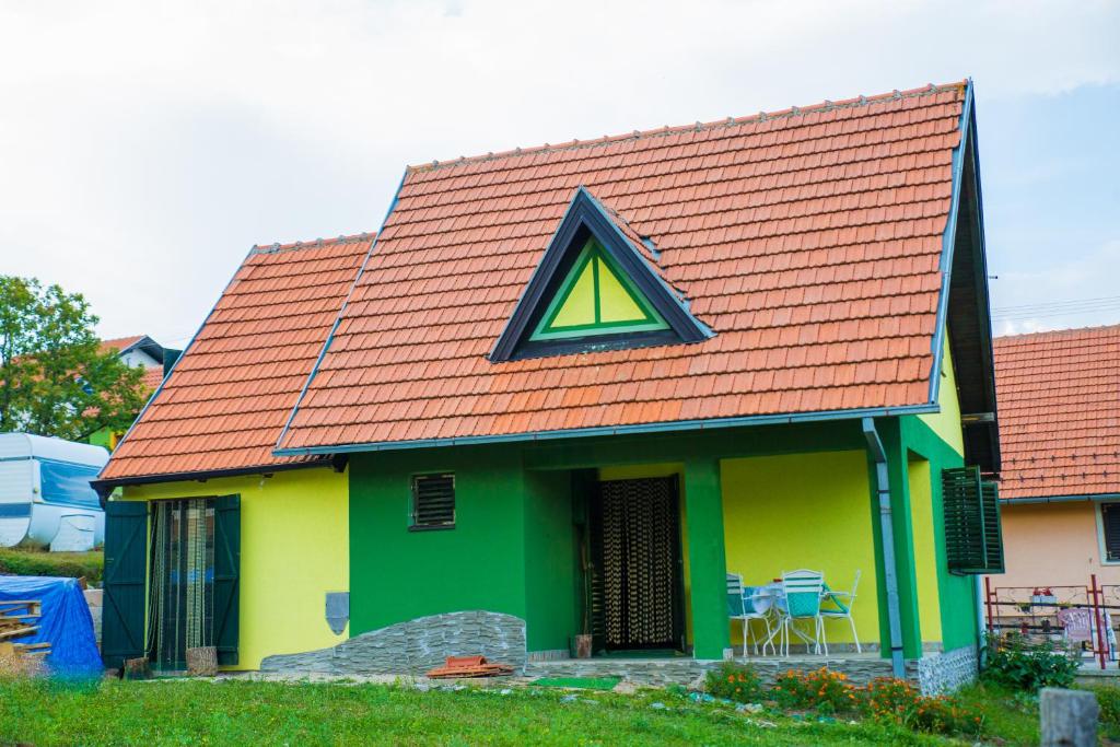 a green and yellow house with a triangular window at Vikendica MM in Zlatibor
