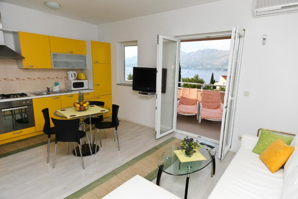 a living room with a white couch and a kitchen at Apartments Villa Ana in Cavtat