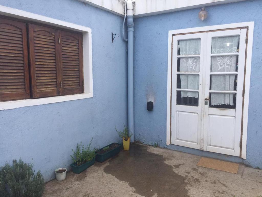 una casa azul con una puerta blanca y algunas plantas en Benito Soria 137 en Santa Rosa de Calamuchita