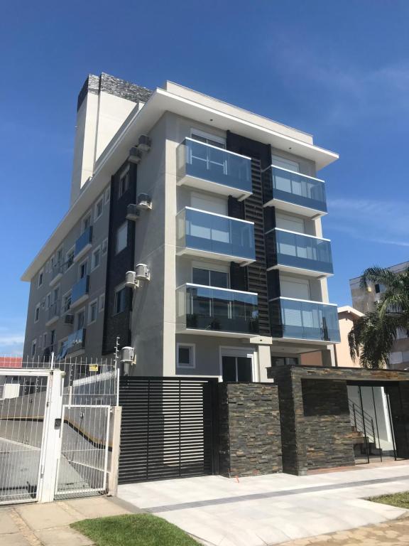 a tall apartment building with a fence in front of it at Ocean Life in Florianópolis